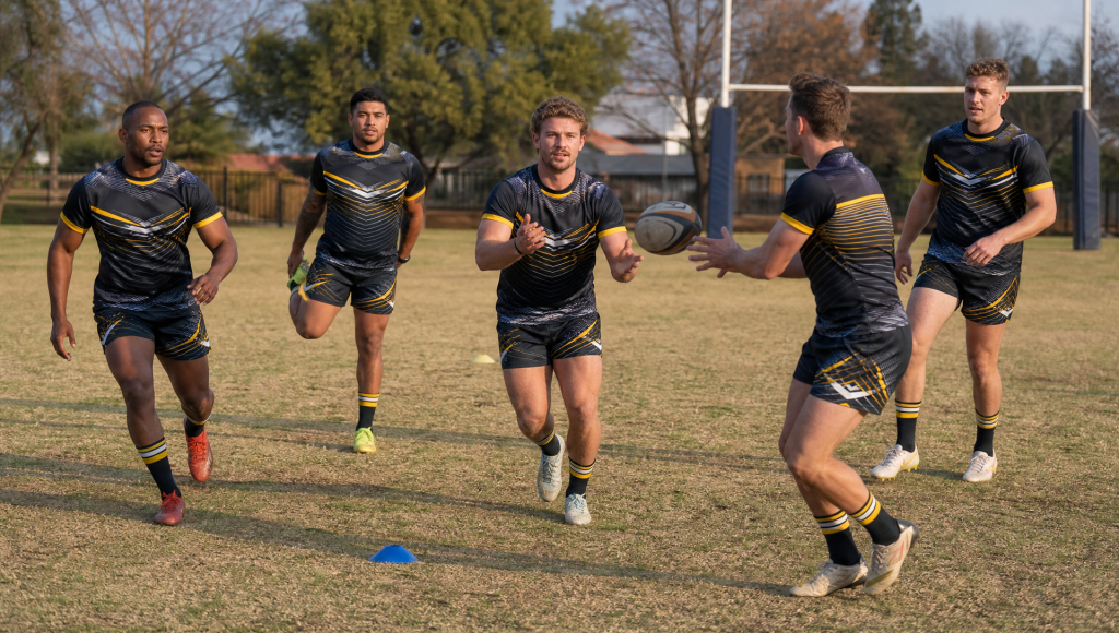All-male Pretoria rugby team warming up in matching custom sportswear on a local field.